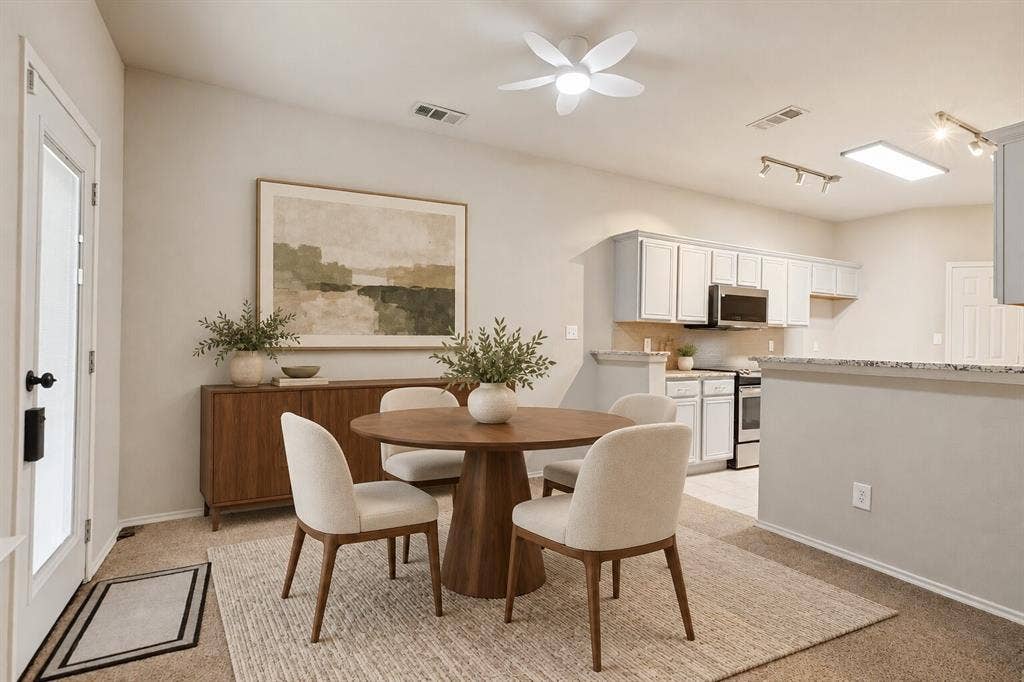 Kitchen featuring a raised breakfast bar with stone-finish countertops, white cabinetry, integrated track lighting, and a multi-blade ceiling fan