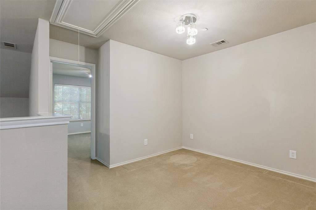 Neutral-toned interior space featuring wall-to-wall carpeting, a multi-light polished chrome chandelier, and a decorative ceiling access panel