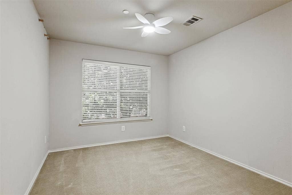 Neutral interior space featuring carpeted flooring, a multi-blade ceiling fan with integrated lighting, and a large window fitted with horizontal blinds