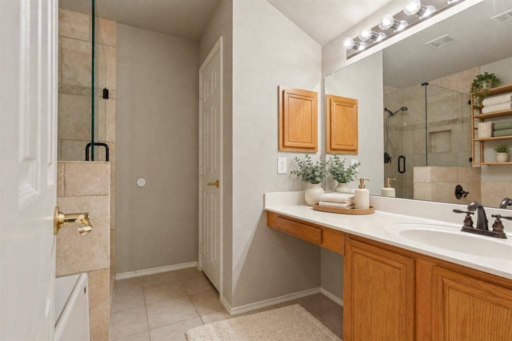Bathroom featuring a vanity with wood cabinetry, a solid surface countertop, an oval undermount sink, and a large wall-mounted mirror