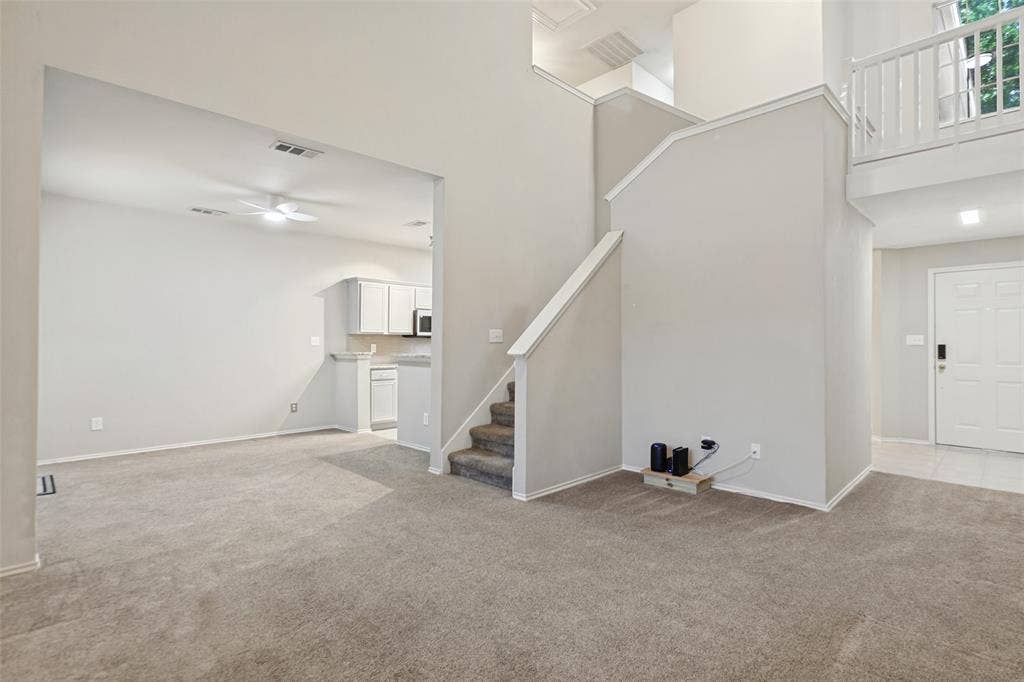 Open-concept interior featuring vaulted ceilings, a staircase with a white railing, and a lofted landing