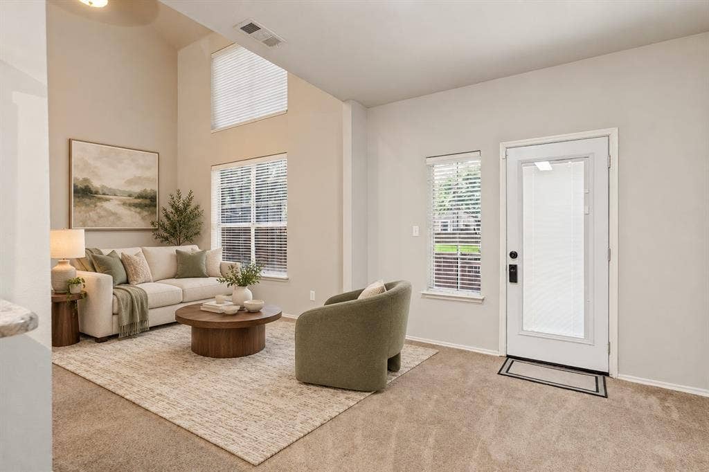 Vaulted ceilings, expansive windows with horizontal blinds, and a glass-paneled exterior door