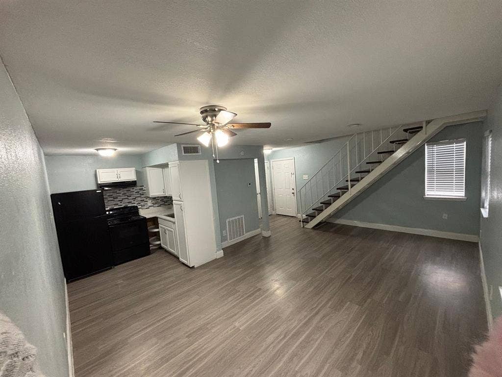 301 Rolston Road, #307-103, Irving, TX 75060 Kitchen featuring white cabinetry, patterned backsplash, and built-in appliances, accented by wood-finish flooring and an architectural staircase