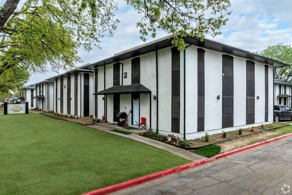 301 Rolston Road, #307-103, Irving, TX 75060 Two-story exterior featuring white stucco siding, dark vertical accent panels, overhanging gabled entry covers, and exterior wall-mounted light fixtures