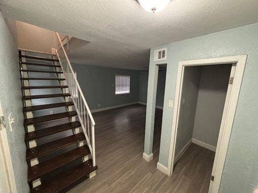 301 Rolston Road, #307-103, Irving, TX 75060 Staircase with wooden treads and white metal railing, wood-finish flooring, and recessed ceiling lighting
