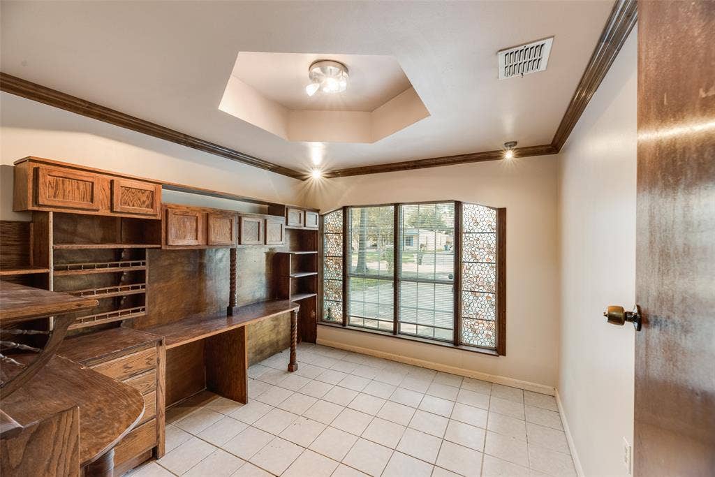 1572 Gillette Circle, Dallas, TX 75217 Built-in wood cabinetry with integrated desk surface, hexagonal tray ceiling, ceramic tile flooring, and decorative lattice-patterned window side panels