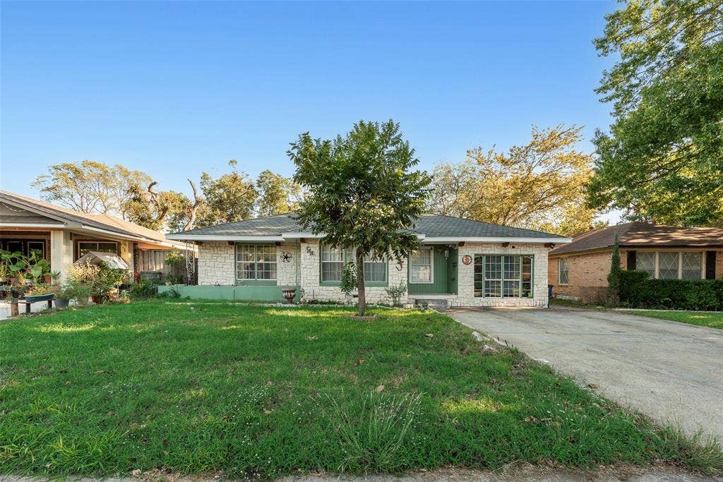 1572 Gillette Circle, Dallas, TX 75217 Single-story residence featuring a light-toned stone exterior, expansive front lawn, multi-pane windows, and a dedicated concrete driveway