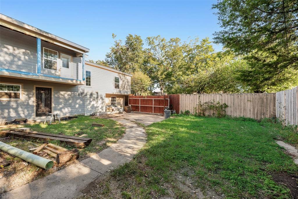 1572 Gillette Circle, Dallas, TX 75217 Rear yard featuring a concrete patio path, wood-panel exterior siding, and perimeter wood fencing