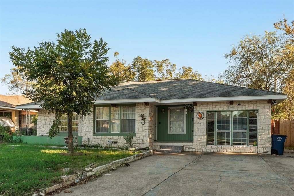 1572 Gillette Circle, Dallas, TX 75217 Stone exterior facade with a low-pitched roof, multi-pane windows, and a concrete driveway