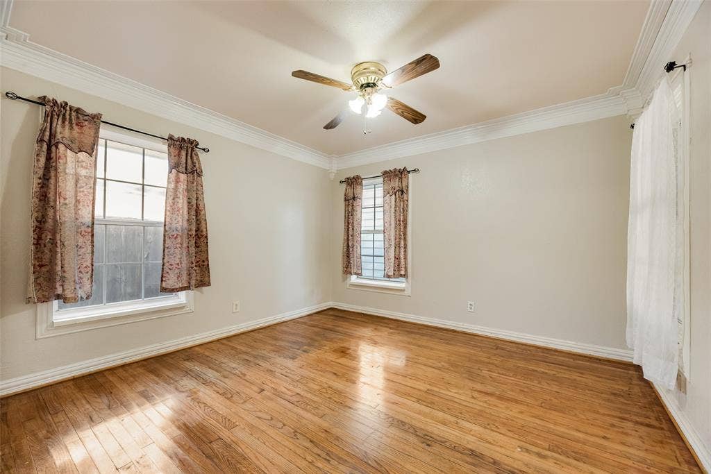 1572 Gillette Circle, Dallas, TX 75217 Room featuring wood-finish flooring, crown molding, and a ceiling fan with integrated lighting, accented by two windows with multi-pane glass