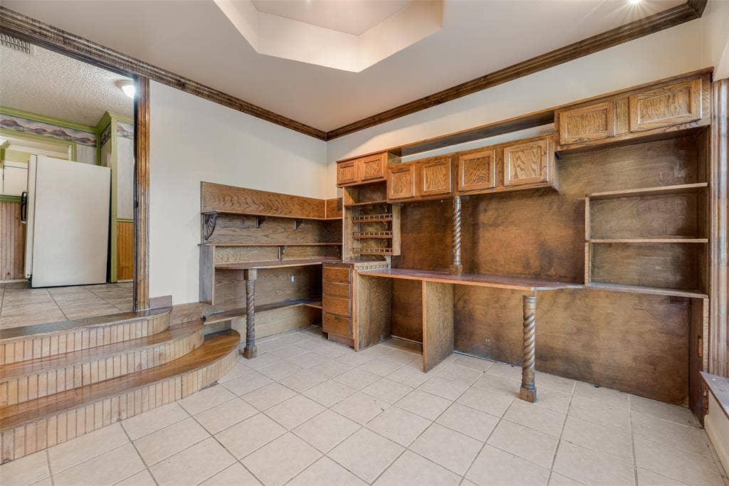 1572 Gillette Circle, Dallas, TX 75217 Custom built-in wood cabinetry, integrated desk workspace, coffered ceiling detail, and wood-trimmed steps