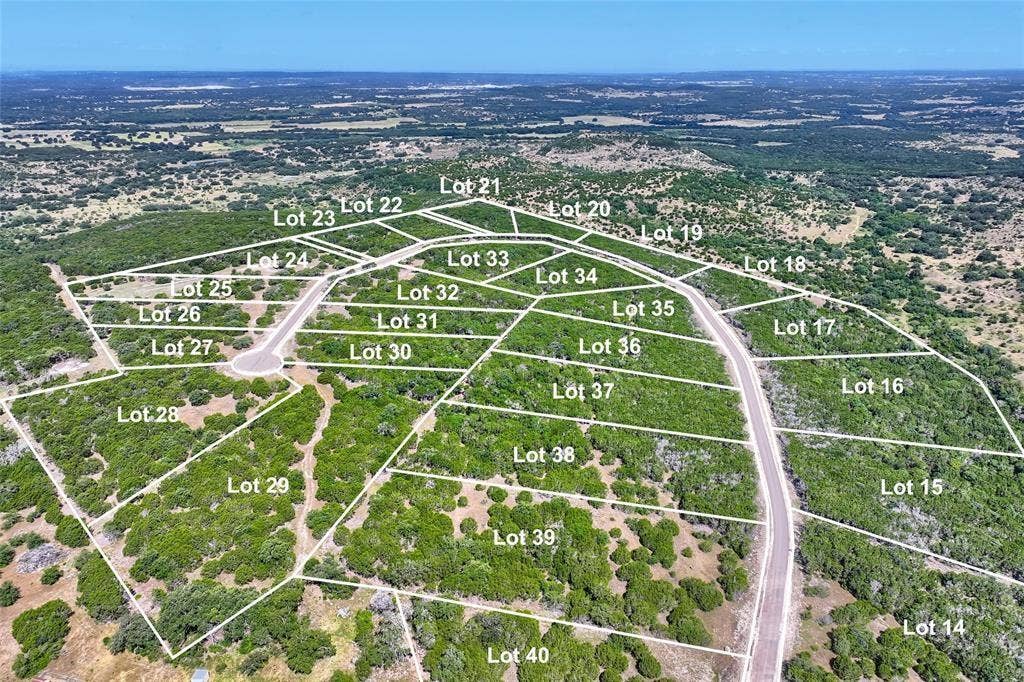 Aerial view of undeveloped land parcels featuring paved road access, varying topography, and native vegetation