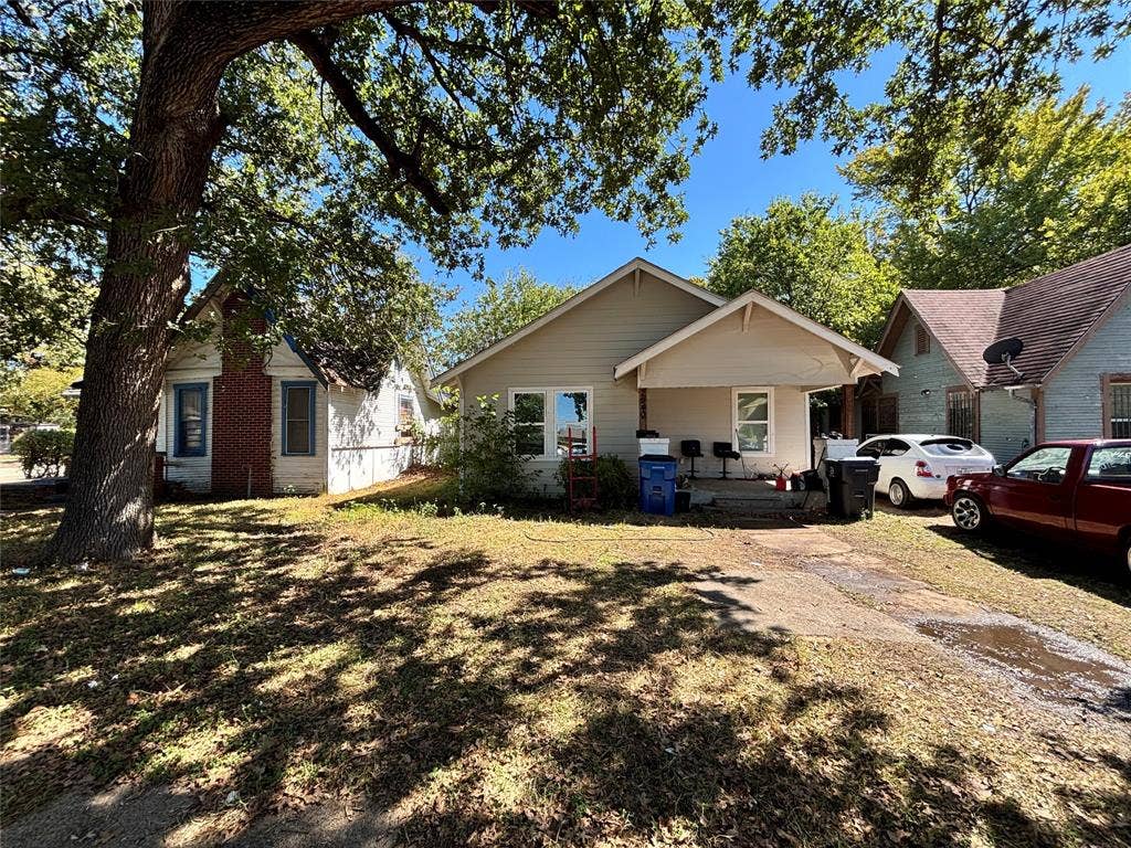 Single-story exterior featuring light-toned horizontal siding, a covered front entry, and mature trees on the lot