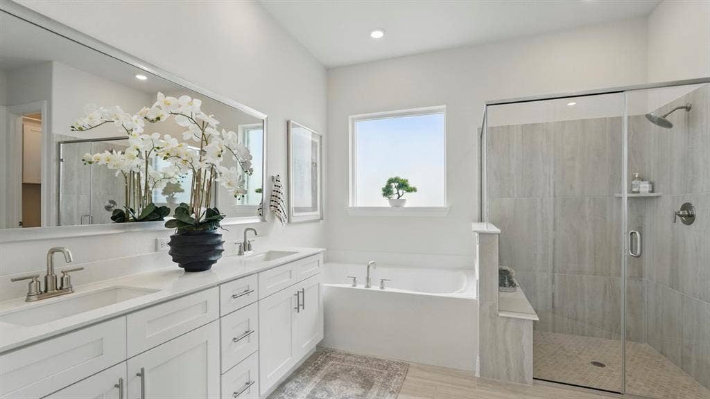 Double vanity featuring white cabinetry, quartz-surface countertops, and a full-width mirror, accompanied by a soaking tub and a walk-in shower with floor-to-ceiling tile surround