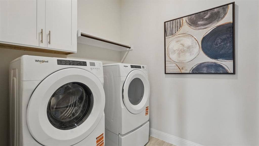 Laundry area featuring white shaker-style wall cabinetry and a built-in shelf