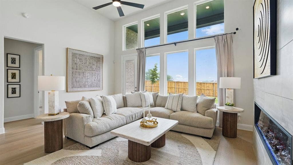 Living area featuring floor-to-ceiling windows, high ceilings, wood-finish flooring, and a linear built-in fireplace with tile surround