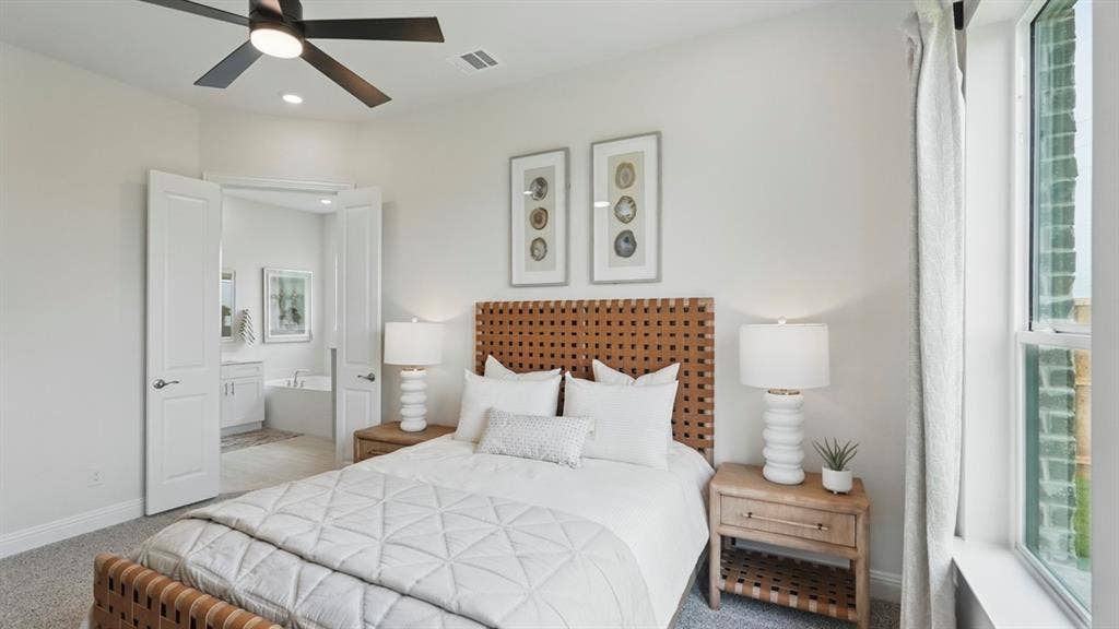 Neutral-toned room featuring plush carpeting, a modern ceiling fan with integrated lighting, and dual-panel interior doors leading to a separate bathroom
