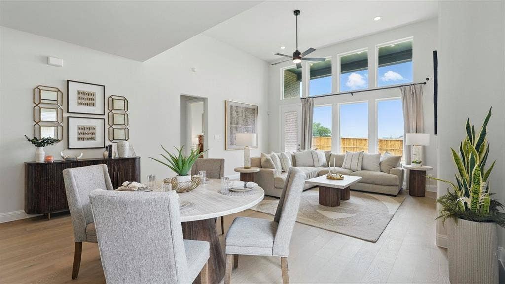 High-ceiling interior featuring a bank of tall windows, light wood-finish flooring, and a ceiling-mounted fan