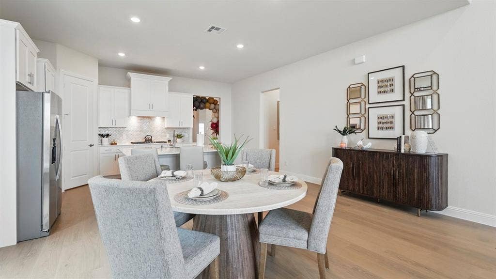 Kitchen featuring white cabinetry, a center island with bar seating, recessed lighting, and wood-finish flooring