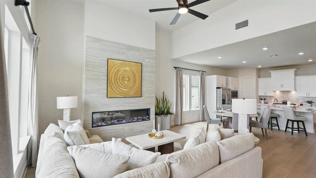High ceilings, stone-finish fireplace surround with linear firebox, wood-finish flooring, and recessed lighting