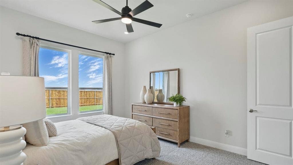 Neutral-toned bedroom featuring plush wall-to-wall carpeting, dual pane windows, and a matte black ceiling fan with integrated lighting