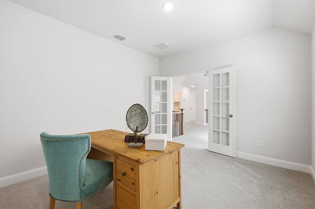 Vaulted ceiling with neutral carpeting and glass-paned French doors