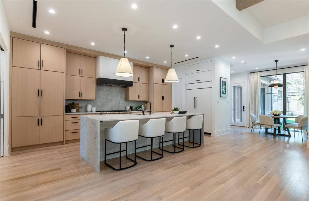 6979 Bob O Link Drive, Dallas, TX 75214 Kitchen featuring light wood-finish cabinetry, a waterfall-edge center island, stone-surround backsplash, recessed lighting, and wood-finish flooring