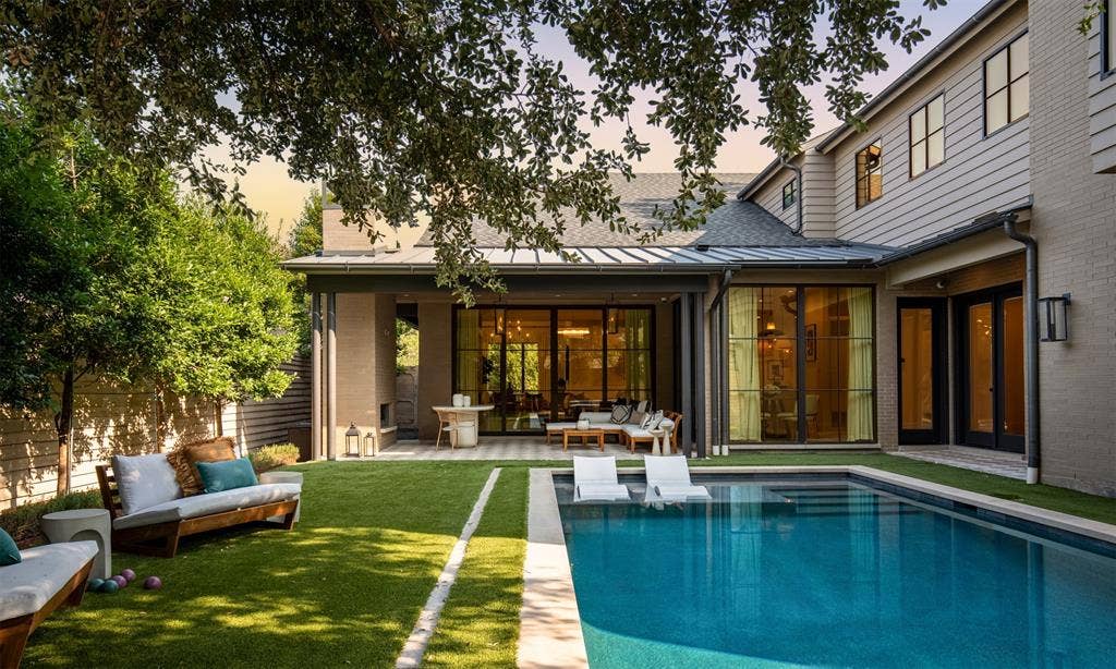 6979 Bob O Link Drive, Dallas, TX 75214 Outdoor living space featuring a covered patio with metal roofing, an in-ground pool with a tanning ledge, expansive floor-to-ceiling glass panel doors, brick and horizontal siding exterior, and a manicured lawn
