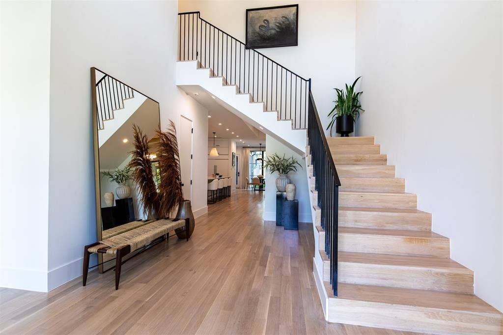6979 Bob O Link Drive, Dallas, TX 75214 Entryway featuring wood-finish flooring, a staircase with custom light-toned wood treads, and minimalist black metal railings