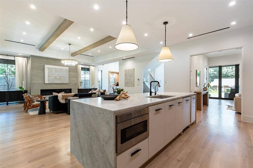 6979 Bob O Link Drive, Dallas, TX 75214 Kitchen island featuring a waterfall stone countertop, integrated microwave, and undermount sink with a matte black faucet