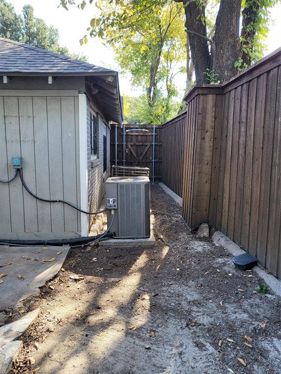 2705 Tanner Street, Dallas, TX 75215 Exterior side yard featuring vertical siding, masonry wall construction, a dedicated HVAC unit on a concrete pad, and full-height wood fencing