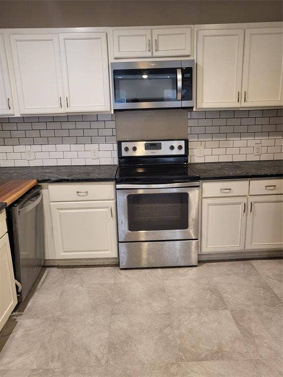 2705 Tanner Street, Dallas, TX 75215 Kitchen featuring white shaker-style cabinetry, dark stone-finish countertops, stainless steel appliances, subway tile backsplash, and neutral-tone tile flooring