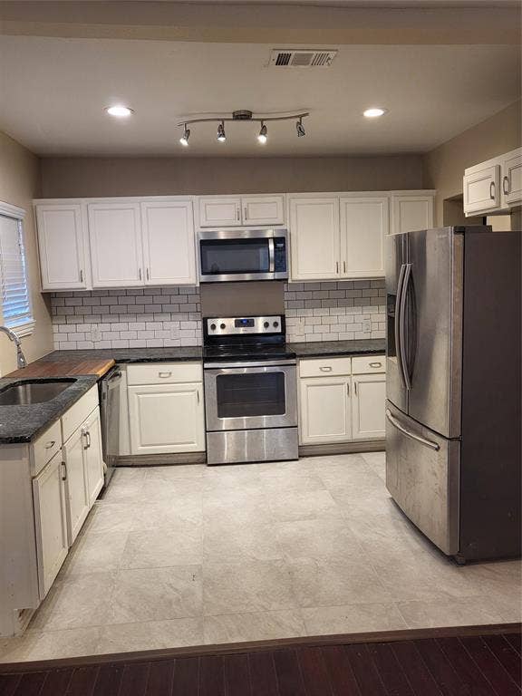 2705 Tanner Street, Dallas, TX 75215 Kitchen featuring white shaker-style cabinetry, dark stone countertops, stainless steel appliances, subway tile backsplash, and ceramic tile flooring