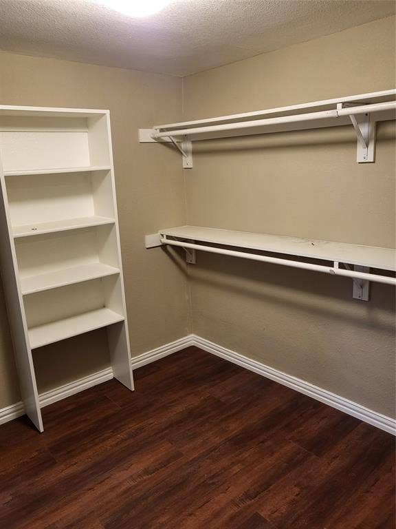 2705 Tanner Street, Dallas, TX 75215 Storage area featuring wood-finish flooring, white built-in shelving unit, and dual tiers of wall-mounted hanging rods