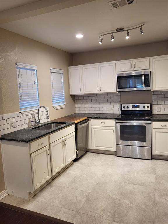 2705 Tanner Street, Dallas, TX 75215 Kitchen featuring white shaker-style cabinetry, stone-finish countertops, subway tile backsplash, stainless steel appliances, and adjustable track lighting