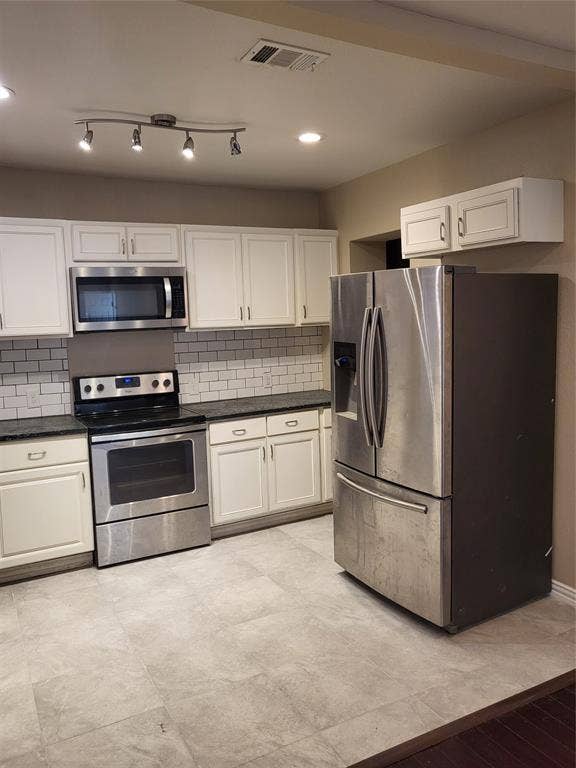 2705 Tanner Street, Dallas, TX 75215 Kitchen featuring white shaker-style cabinetry, stainless steel appliances, dark stone countertops, subway tile backsplash, and large-format tile flooring