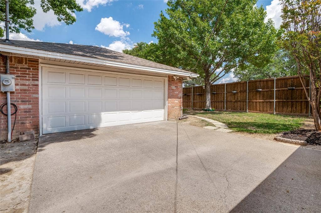 Attached two-car garage with paneling, brick exterior, and concrete driveway