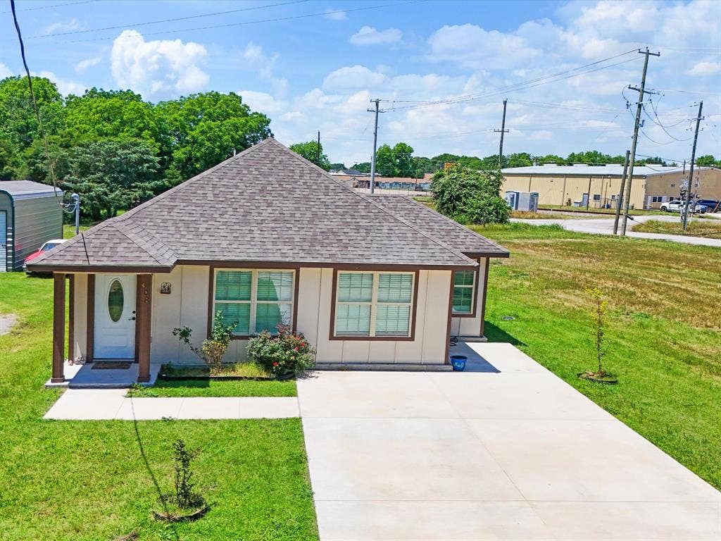 Single-story exterior featuring a hip roof, exterior trim accents, concrete driveway, and covered front entry