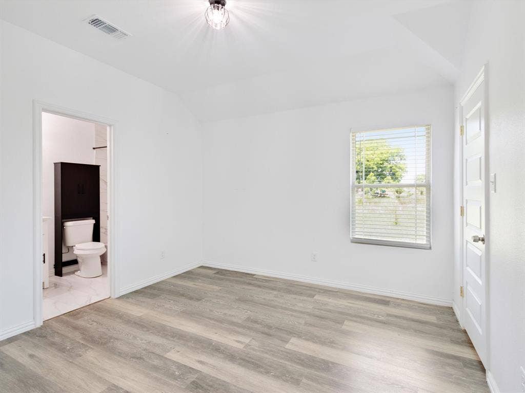 Neutral-toned wood-finish flooring, vaulted ceilings, and a multi-pane window with horizontal blinds