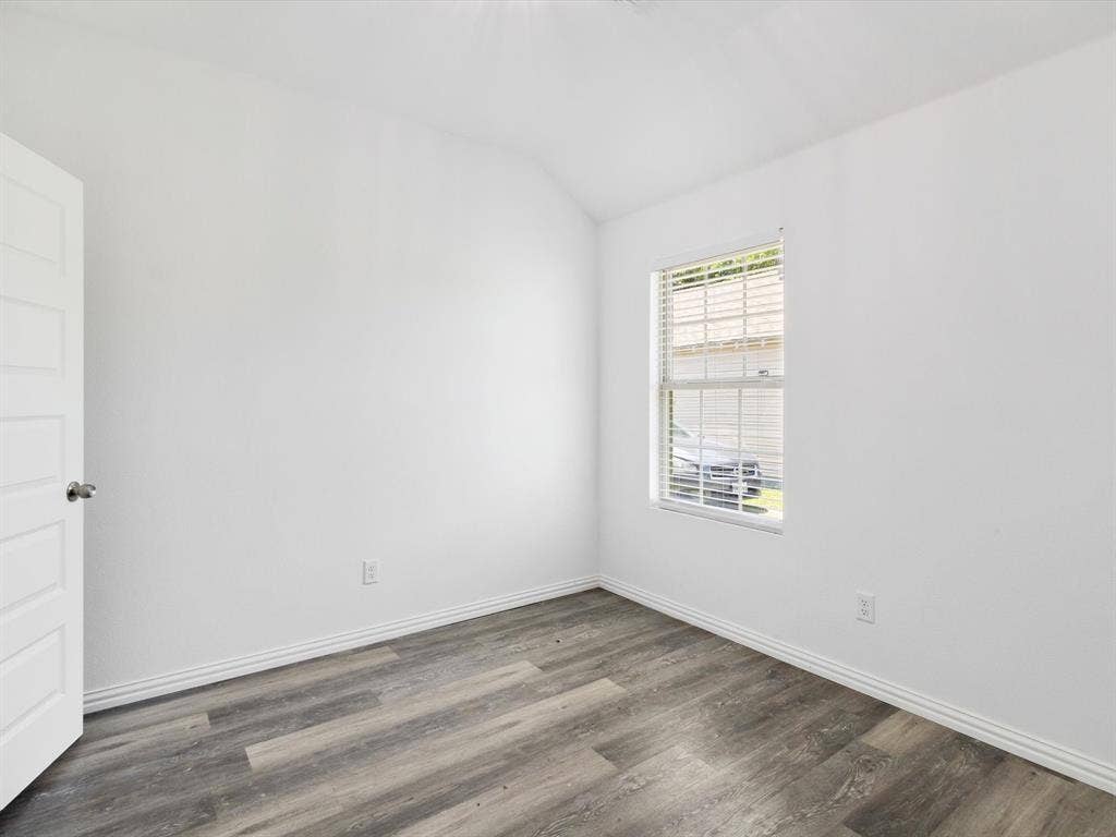Interior space featuring wood-finish flooring, a neutral color palette, a multi-pane window with blinds, and a five-panel interior door