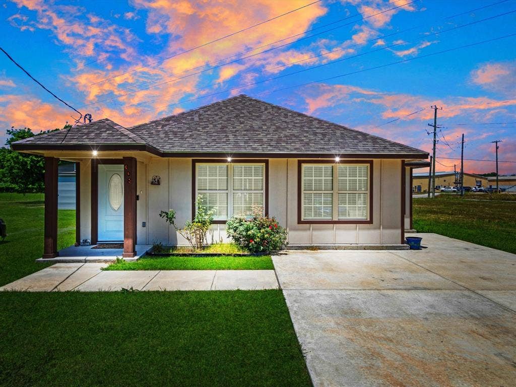 Single-story residence featuring a hipped shingle roof, covered front entryway with square columns, concrete driveway, and multi-pane windows