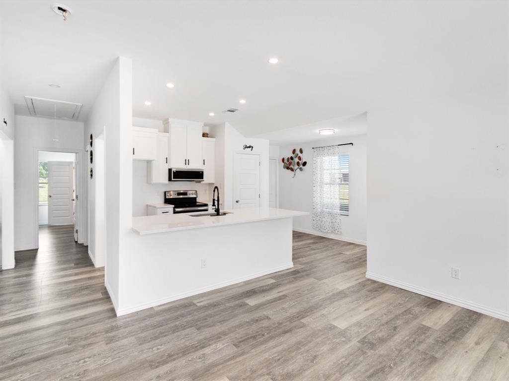 Kitchen featuring white cabinetry, an island with stone-finish countertops, recessed lighting, and wood-finish flooring