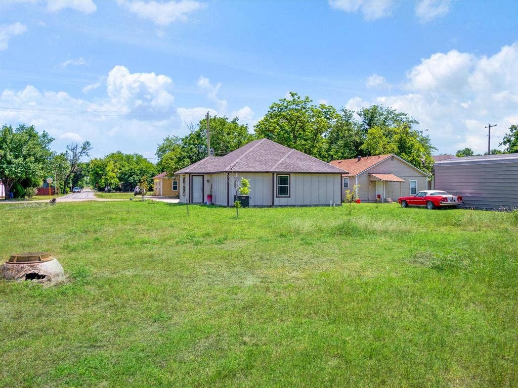 Expansive lot featuring mature trees, grass lawn, and a detached structure with a hip roof