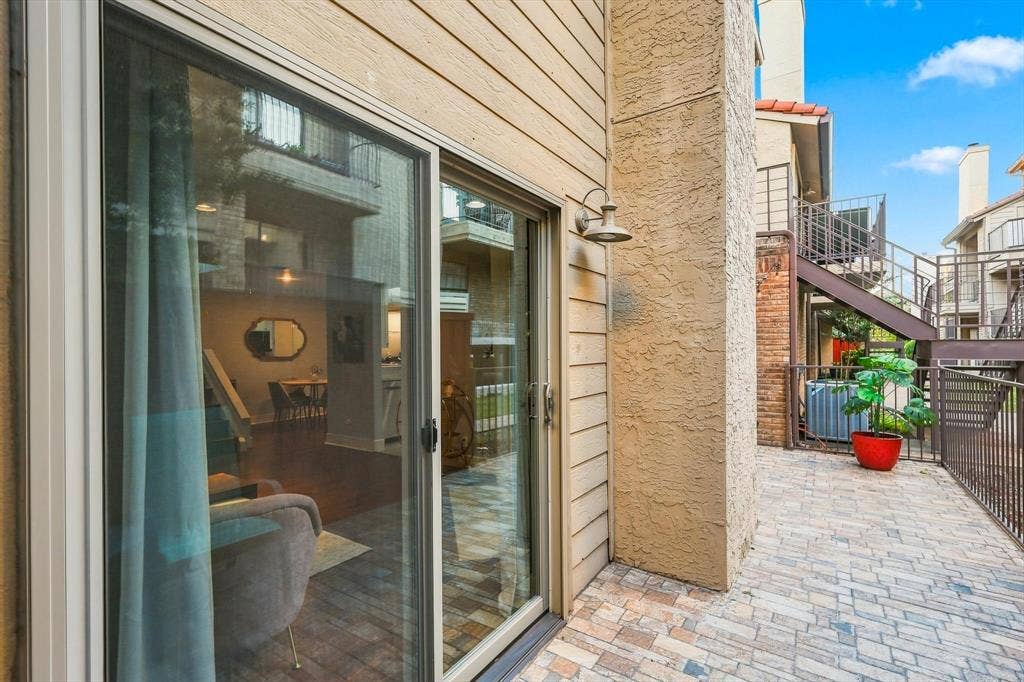 4777 Cedar Springs Road, #9K, Dallas, TX 75219 Private patio featuring stone-paver flooring, horizontal lap siding, brick accent wall, and exterior gooseneck lighting