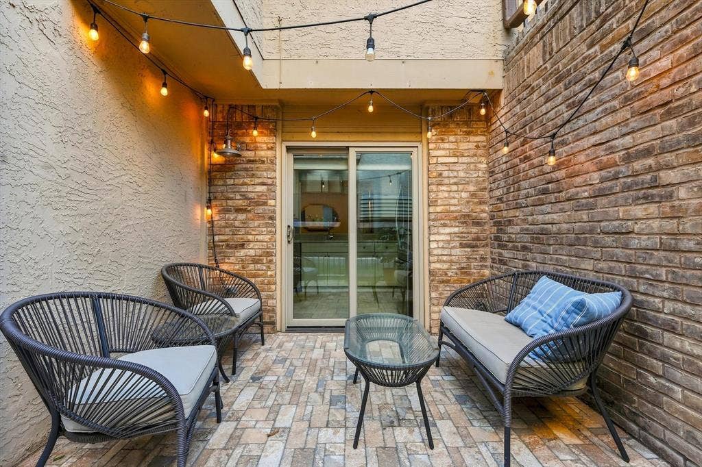 4777 Cedar Springs Road, #9K, Dallas, TX 75219 Enclosed courtyard featuring masonry brick walls, textured stucco siding, multi-tone stone paver flooring, and sliding glass entry doors