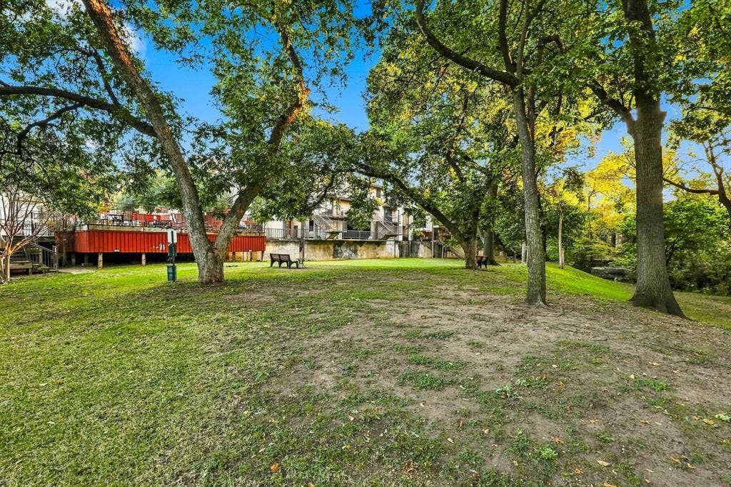 4777 Cedar Springs Road, #9K, Dallas, TX 75219 Expansive green space featuring mature trees and a raised wooden deck with railings