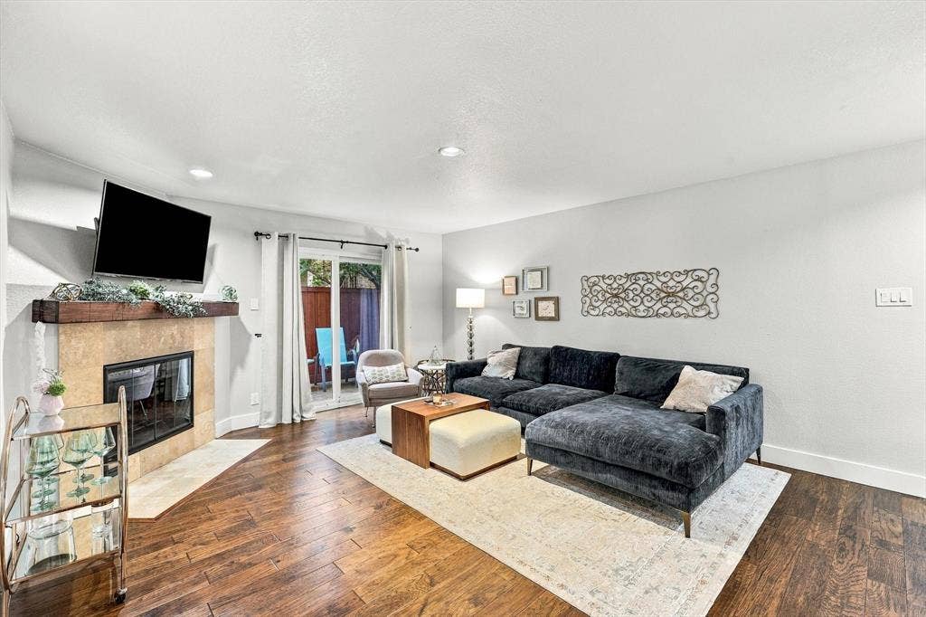 4777 Cedar Springs Road, #9K, Dallas, TX 75219 Living space featuring dark wood-finish flooring, recessed lighting, and a fireplace with a stone-surround facade and timber mantel
