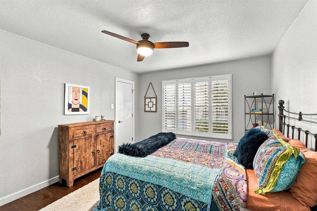 4777 Cedar Springs Road, #9K, Dallas, TX 75219 Neutral-toned interior featuring wood-finish flooring, a ceiling fan with integrated lighting, and plantation shutters