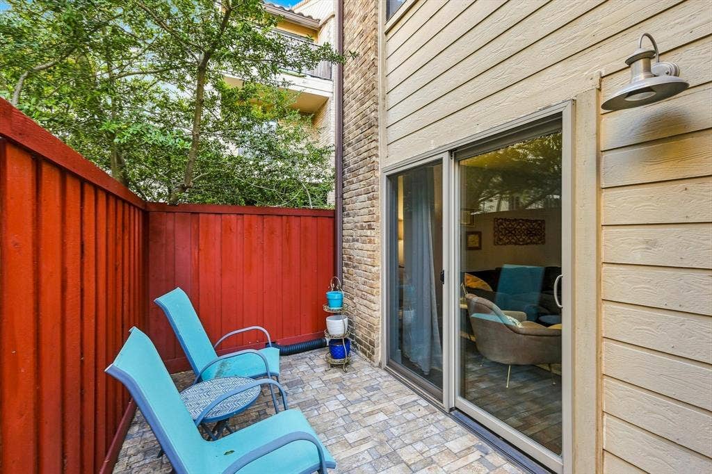 4777 Cedar Springs Road, #9K, Dallas, TX 75219 Private patio featuring stone-paver flooring, horizontal lap siding, brick accent wall, and exterior gooseneck lighting
