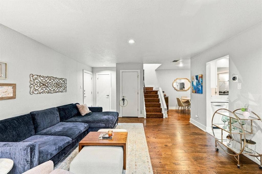 4777 Cedar Springs Road, #9K, Dallas, TX 75219 Open-concept interior featuring wood-finish flooring, staircase with carpeted treads, and neutral wall tones